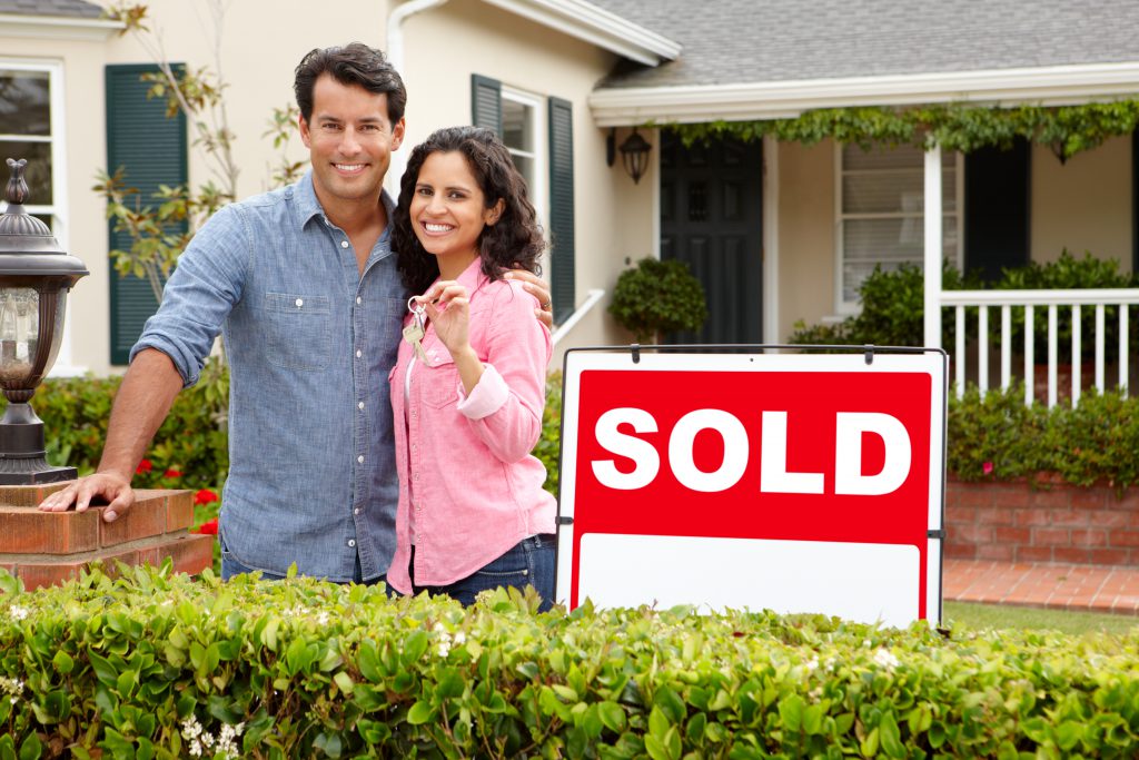 stock-photo-hispanic-couple-outside-home-with-sold-sign